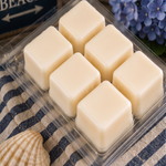 Six cream soy wax cubes in an open Noepe clamshell on a navy striped towel