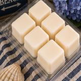 Six cream soy wax cubes in an open Noepe clamshell on a navy striped towel