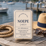 Noepe wax melts clamshell on a wooden table with a straw hat and sunglasses