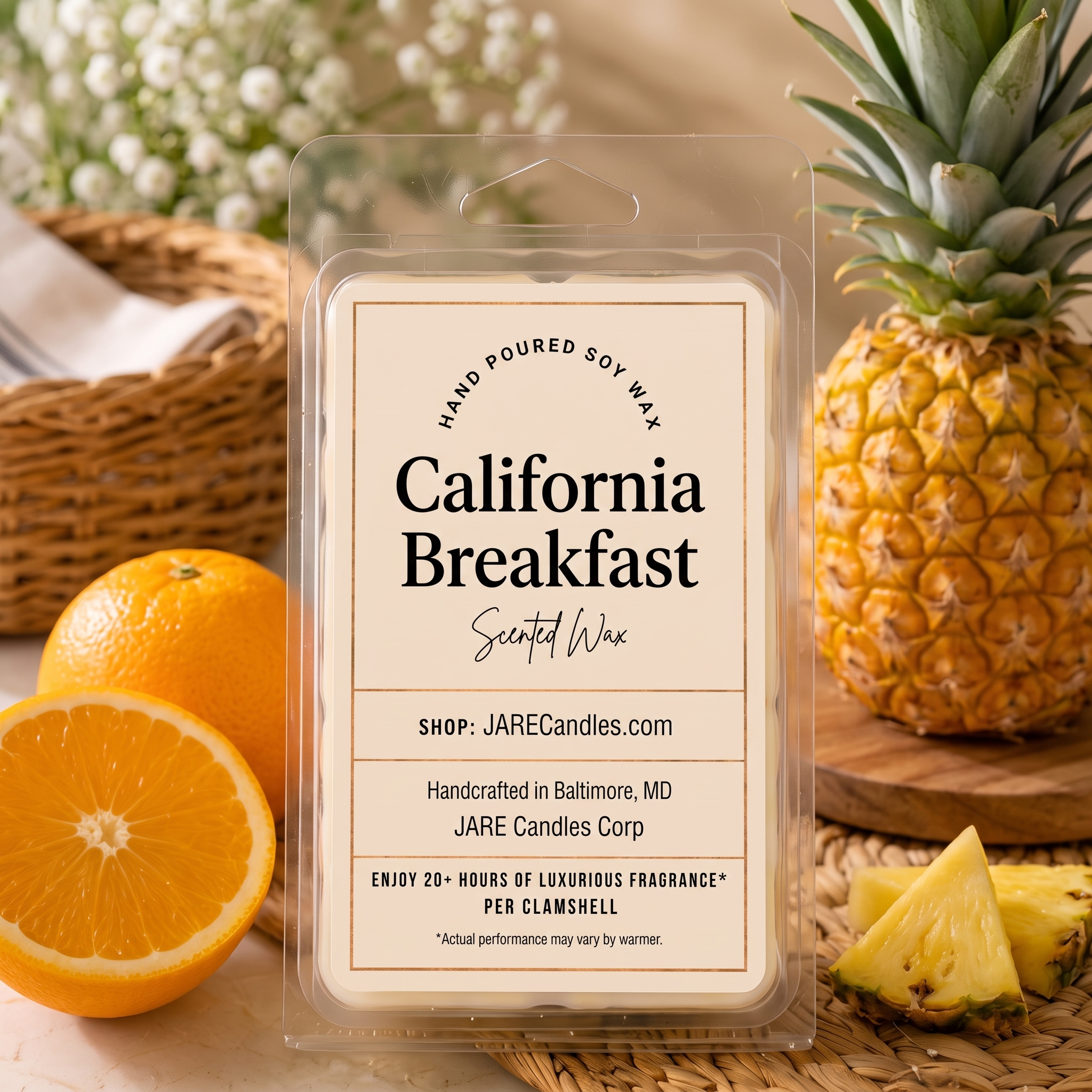 California Breakfast scented wax melt clamshell by JARE Candles, styled with fresh oranges and a whole pineapple on a woven rattan mat in warm morning light