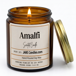 Amalfi 5oz amber jar candle, lit, lid resting against jar
