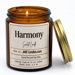 Harmony 5oz amber jar candle, lit, lid resting against jar