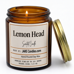 Lemon Head 5oz amber jar candle, lit, lid resting against jar