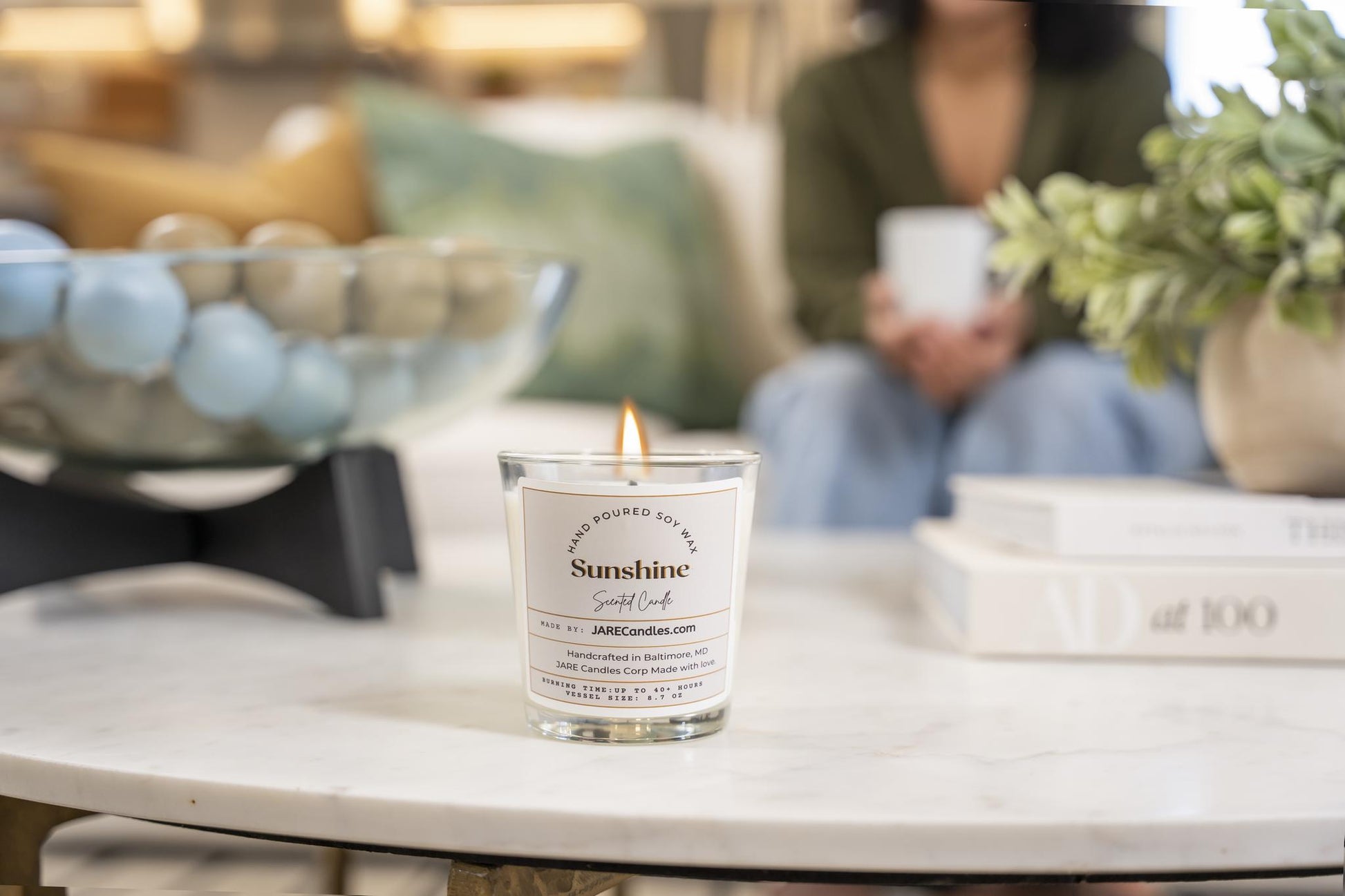 Lit JARE Candles Sunshine candle on marble coffee table in relaxed living room scene